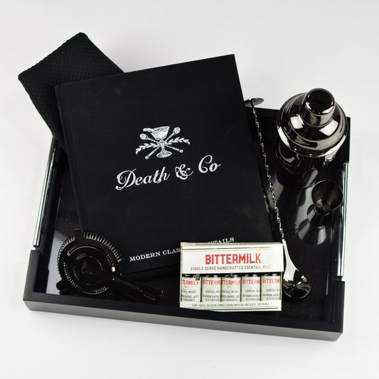 Black tray, black cocktail accessories, black velvet gift bag, package of Bittermilk cocktail mixers, Death & Co cocktail book