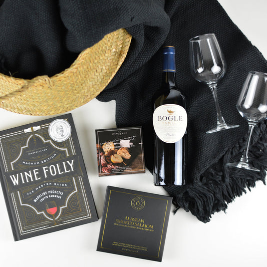 Seagrass basket bucket, one bottle of Bogle wine, two wine glasses, black plush blanket with tassles, cabernet cheese spread, small box of smoked salmon, and Wine Folly book